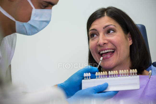 Dentist examining female patient with teeth shades at dental clinic — Stock Photo