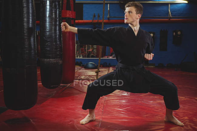 Jeune joueur de karaté adulte effectuant position de karaté dans un studio de fitness — Photo de stock