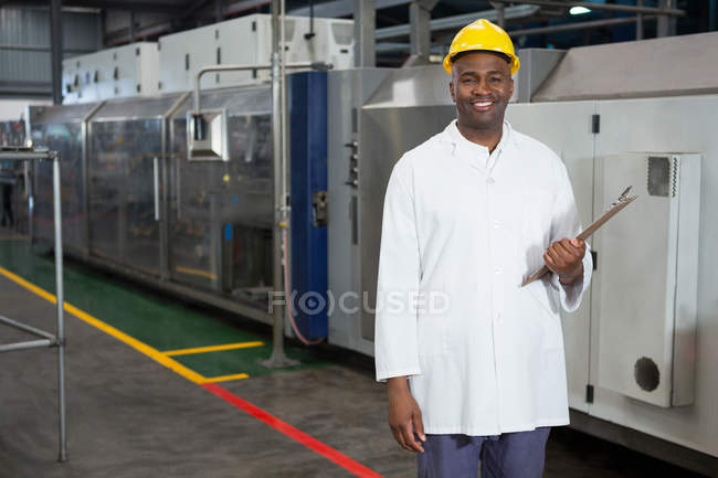 Retrato del trabajador masculino sonriente sosteniendo el portapapeles en el almacén - foto de stock