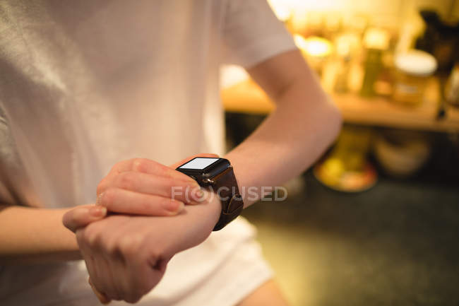 Mid-section of woman using smart watch at home — Stock Photo