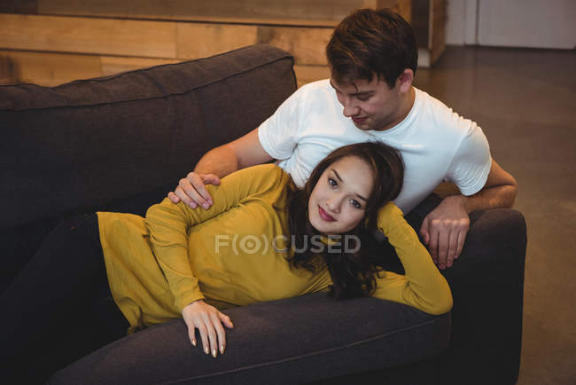 Pareja alegre tumbados juntos en el sofá en la sala de estar en casa - foto de stock