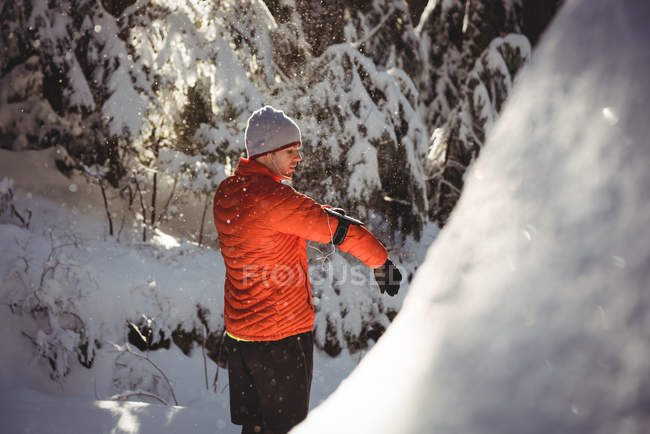 Человек слушает музыку в наушниках со смартфона зимой — стоковое фото