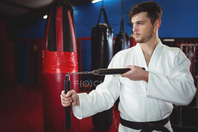 Karate player practicing with nunchaku in fitness studio — Stock Photo
