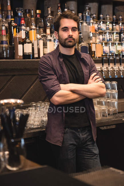 Portrait of a confident bartender standing at bar counter — Stock Photo