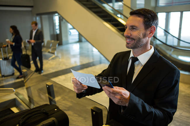 Empresário titular de cartão de embarque e passaporte no terminal do aeroporto — Fotografia de Stock