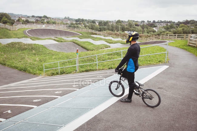 Велогонщик, стоящий на велосипеде BMX на стартовой рампе в скейтпарке — стоковое фото