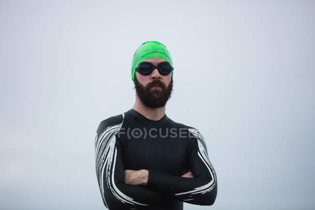 Portrait of athlete in wet suit standing with his hands crossed — Stock Photo
