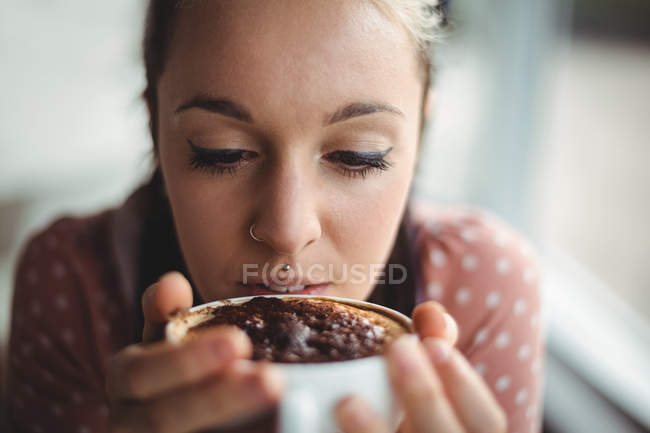 Primer plano de la mujer sonriente tomando una taza de café en la cafetería - foto de stock