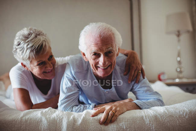 Счастливая пожилая пара лежит на кровати в спальне — стоковое фото