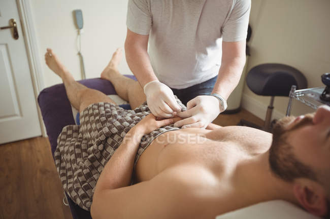 Fisioterapeuta realizando agujas secas a mano del paciente masculino en clínica - foto de stock