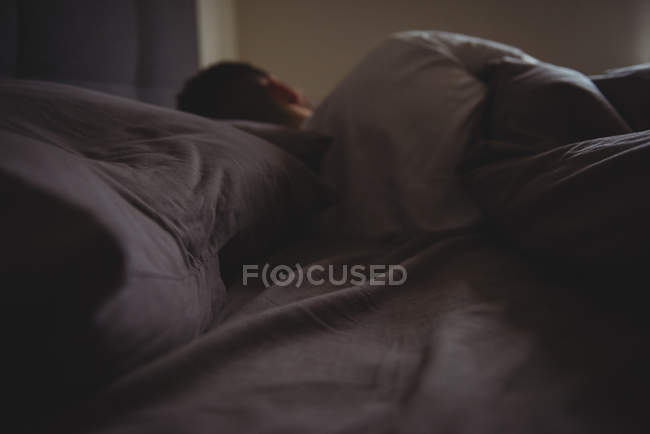 Vue arrière de l'homme dormant dans son lit dans la chambre à coucher à la maison — Photo de stock
