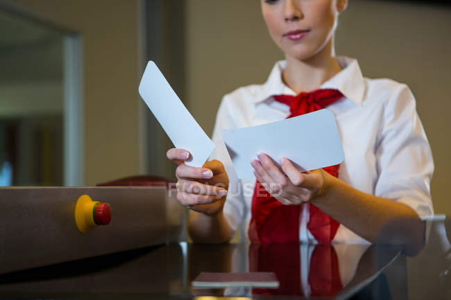 Mid section of female staff holding boarding passes at airport terminal — Stock Photo