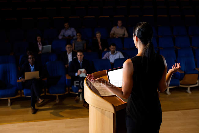 Rear view of female business executive giving a speech at conference center — Stock Photo