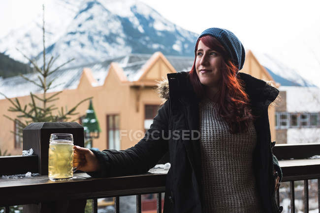 Woman in winter clothing holding beer glass in outdoor terrace — Stock Photo
