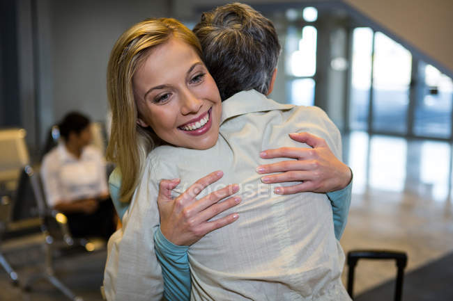 Amigos abrazándose en la sala de espera en la terminal del aeropuerto - foto de stock