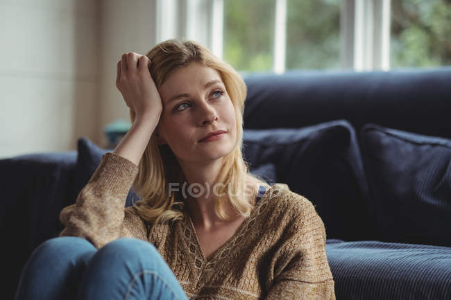 Задумчивая женщина сидит дома в гостиной — стоковое фото