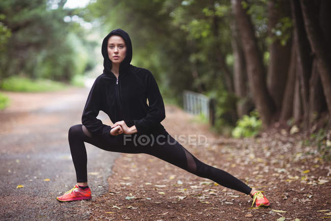 Женщина выполняет упражнения на растяжку в лесу — стоковое фото