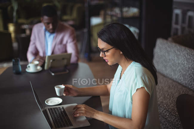 Empresaria usando laptop en oficina - foto de stock
