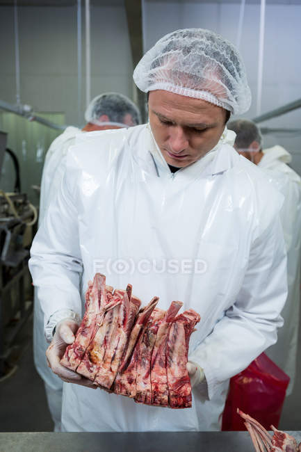 Чоловічий м'ясник тримає м'ясо на м'ясному заводі — стокове фото