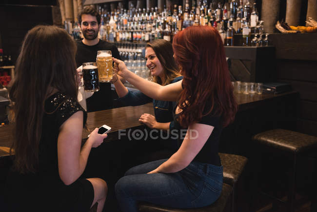 Glückliche Freunde stoßen mit Biergläsern an der Theke an — Stockfoto