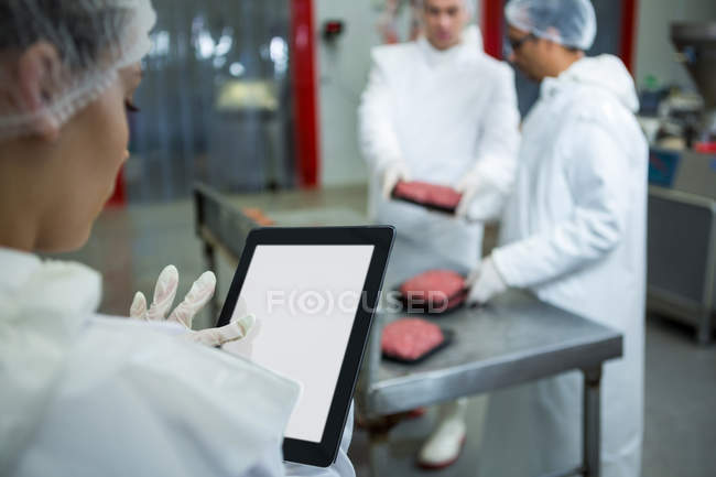 Close-up de técnica feminina usando tablet digital na fábrica de carne — Fotografia de Stock