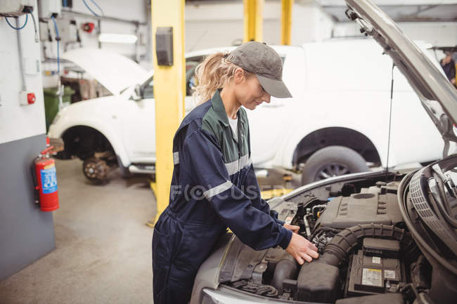 Женщина-механик, обслуживающая машину в ремонтном гараже — стоковое фото