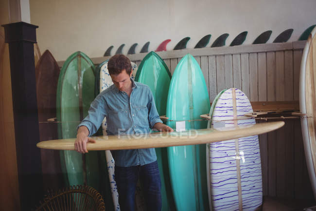 Чоловік вибирає дошку для серфінгу в майстерні — стокове фото