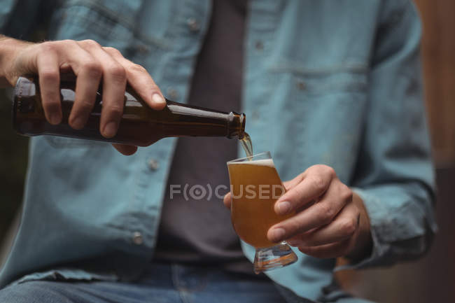 Gros plan d'un homme versant de la bière dans un verre à bière — Photo de stock