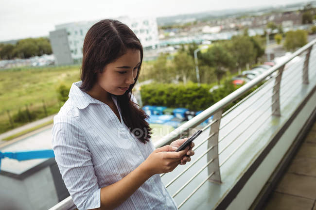 Junge Geschäftsfrau nutzt Handy auf Bürobalkon — Stockfoto