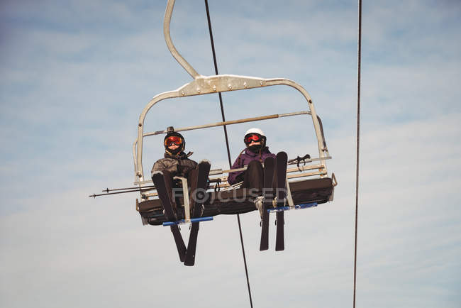 Vista en ángulo bajo de dos esquiadores que viajan en telesilla en la estación de esquí - foto de stock