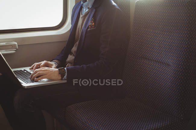 Mid-section of businessman using laptop while travelling in train — Stock Photo