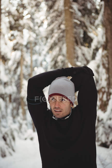 Thoughtful man stretching arms in forest during winter — Stock Photo