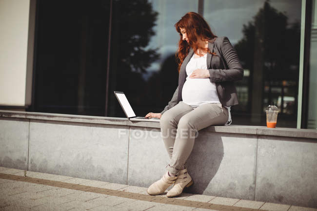 Schwangere Geschäftsfrau benutzt Laptop in Büroräumen — Stockfoto