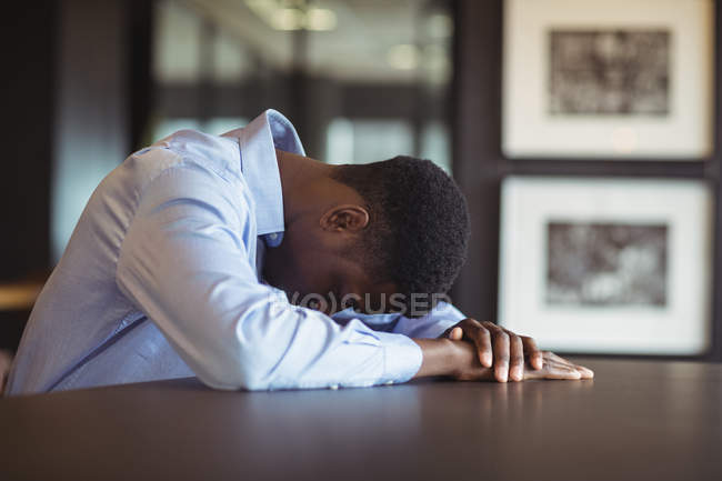 Hombre de negocios estresado sentado en su escritorio en la oficina - foto de stock