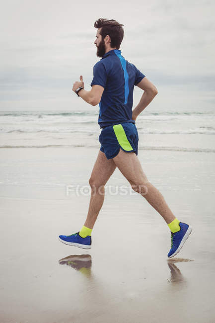 Красивый спортсмен бегает по песчаному пляжу — стоковое фото
