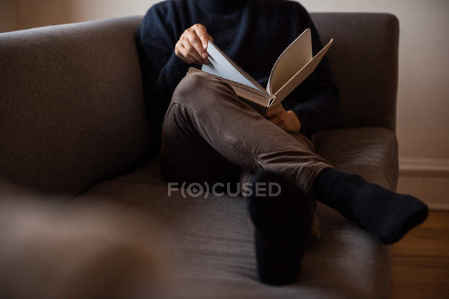 Uomo lettura libro in soggiorno a casa — Foto stock