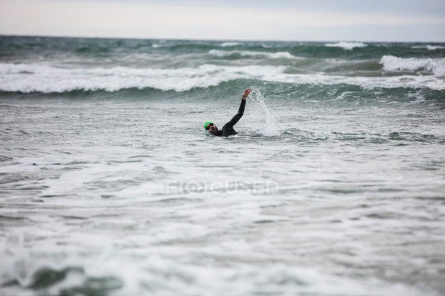 Atleta de terno molhado nadando na água do mar — Fotografia de Stock
