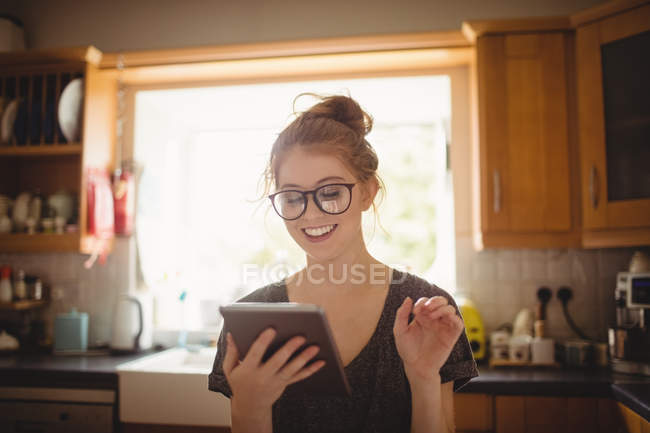 Donna sorridente che utilizza tablet digitale in cucina a casa — Foto stock