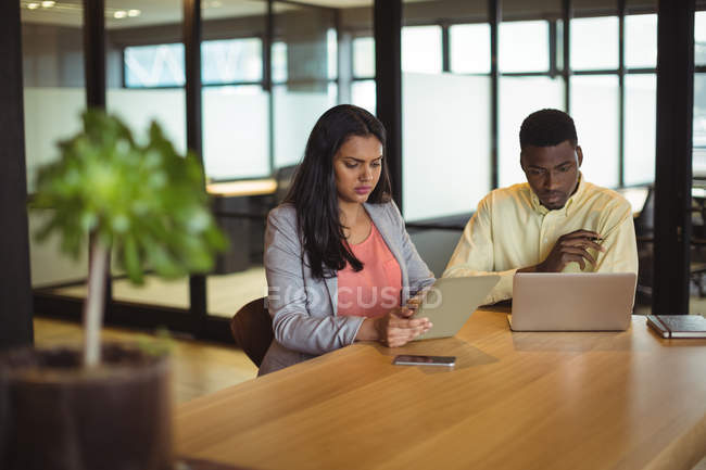 Бизнесмен и коллега работают над цифровым планшетом и ноутбуком в офисе — стоковое фото