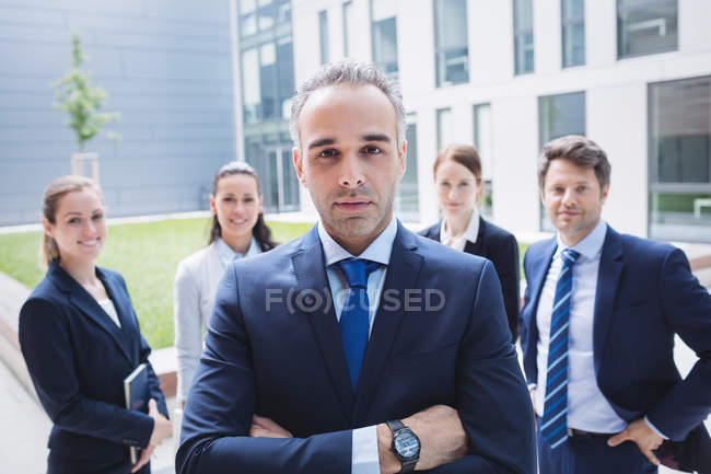 Porträt eines selbstbewussten Geschäftsmannes mit Kollegen, die vor einem Bürogebäude stehen — Stockfoto