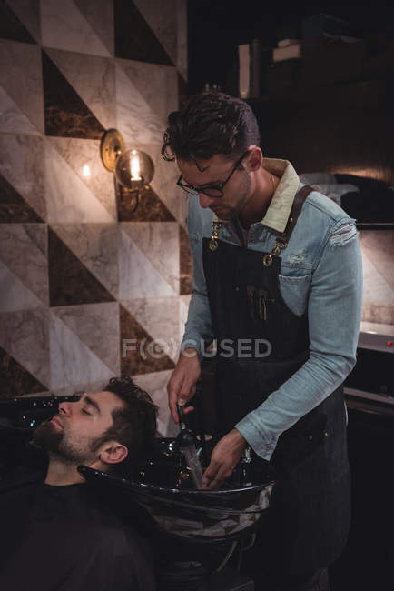 Uomo ottenere lavaggio dei capelli da parrucchiere in negozio di barbiere — Foto stock