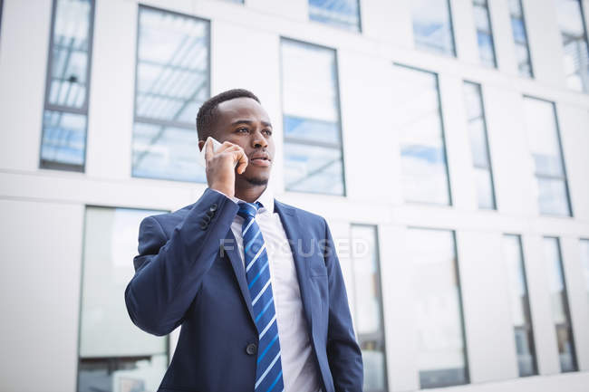 Uomo d'affari che parla sul cellulare fuori dall'edificio degli uffici — Foto stock