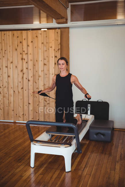 Mulher adulta média praticando pilates no reformador no estúdio de fitness — Fotografia de Stock