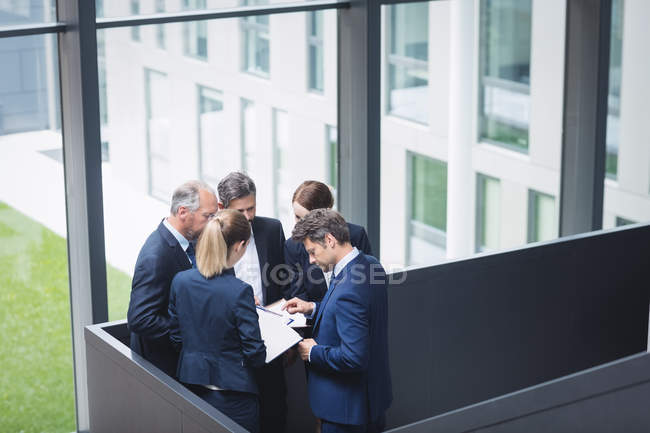Grupo de empresarios teniendo una discusión cerca de la escalera en la oficina - foto de stock
