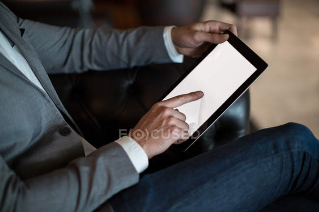 Sección media del hombre de negocios utilizando tableta digital en la zona de espera en la terminal del aeropuerto - foto de stock