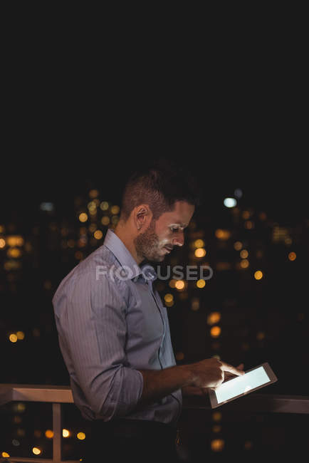 Людина використовує цифровий планшет на балконі вночі — стокове фото
