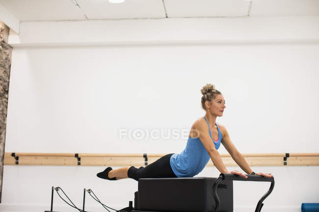 Mitte erwachsene Frau trainiert im Fitnessstudio auf Reformer — Stockfoto
