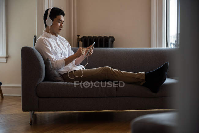 Чоловік слухає музику на цифровому планшеті вдома — стокове фото