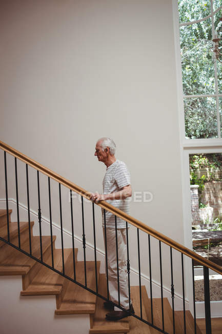 Homem sênior subindo escadas segurando em casa — Fotografia de Stock