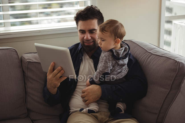 Батько, використовуючи цифровий планшетний під час проведення його дитини вдома — стокове фото